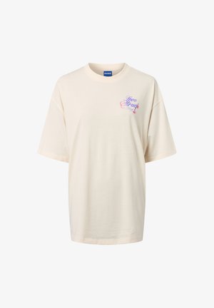 Kremowa bawełniana koszulka z krótkim rękawem. Z przodu, na lewej piersi, znajduje się lekko fioletowy i różowy graficzny wzór z tekstem.