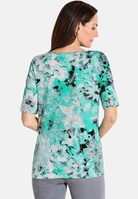 Short-sleeve top in aqua and gray with floral design. Features a loose fit and round neckline. Fabric has a smooth, soft texture.