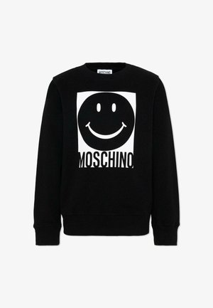 Zwarte Moschino-trui met een groot wit vierkant waarop een zwart glimlachend gezicht staat afgebeeld en daaronder de vetgedrukte tekst "MOSCHINO".