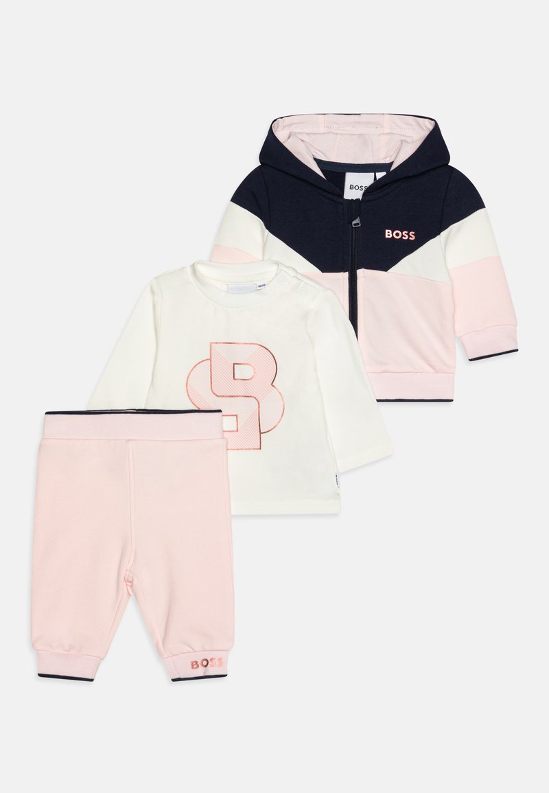Ensemble pour bébé en trois pièces comprenant un hoodie zippé marin et pastel, une chemise à manches longues blanche avec un logo "B" rose, et un pantalon de jogging rose.