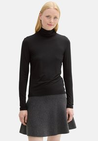 Schwarzes Langarm-Turtleneck-Shirt in tailliertem Design, aus glattem Material, kombiniert mit einem grauen, aus strukturiertem Stoff gefertigten, ausgestellten Rock.