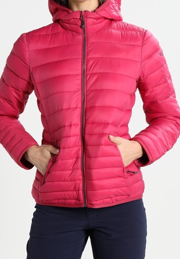 Femme portant une veste matelassée rose vif avec une fermeture éclair à l'avant et les mains dans les poches, associée à un pantalon foncé.