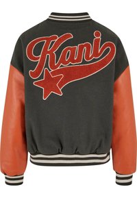 Veste varsity noire avec manches en cuir orange, poignets et ourlets rayés, et grand texte rouge « Kani » avec motif étoile dans le dos.