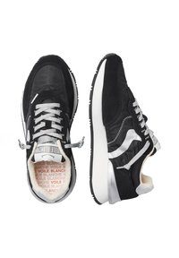 Black sneakers with suede and nylon materials, silver accents, and textured rubber sole. Features grey laces and patterned inner lining.