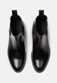 Botas Chelsea de cuero negro con un acabado suave, paneles laterales elásticos y una lengüeta para ponérselas fácilmente. Suelas planas con un mínimo de dibujo.