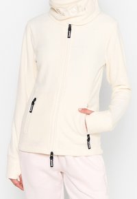 Giacca in pile zip-up crema con colletto alto e dettagli con logo, dotata di due tasche con zip e una vestibilità comoda. Tessuto morbido.