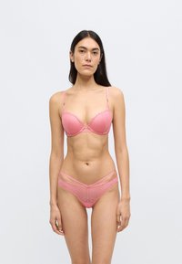 Σετ ροζ δαντελένιο σουτιέν και σλιπ με μπανέλα, οδοντωτές άκρες και γεωμετρικά σχέδια. Περιλαμβάνονται ρυθμιζόμενα λουράκια.