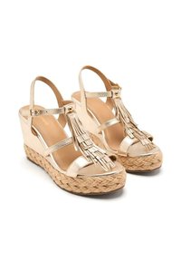 Sandales en or à talon en forme de coin avec des semelles en jute tressé, présentant de multiples accents à franges, des lanières étroites et des brides de cheville ajustables.