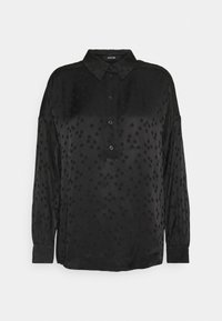 Svart blus med knäppning, med ett subtilt prickmönster. Tillverkad av ett mjukt tyg, har den långa ärmar och en klassisk krage.