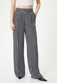Zwart-wit gestreepte wijde broek met hoge taille, voorzien van riemlussen, zijzakken en een gladde stofstructuur.