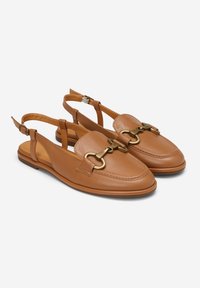 Brązowe skórzane buty typu slingback z zaokrąglonym noskiem, z dużym złotym metalowym detalem w postaci łańcucha i niską podeszwą.