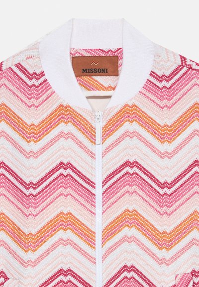 Strick-Bomberjacke in Weiß mit einem Zickzackmuster in Pink-, Rot- und Orangetönen. Verfügt über einen weißen gerippten Kragen und einen Frontreißverschluss.
