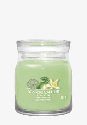 Groene Yankee Candle in glazen pot met illustraties van vanillebloem en limoen, gelabeld "Vanilla Lime," 368 gram.