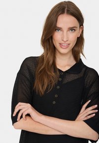 Top negru din tricot cu mâneci scurte, având un guler și accente cu nasturi de culoare aurie. Material texturat cu o croială lejeră.