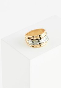 Guld- och silverfärgad ringband med sammanflätade vågor; slät yta; rundad form; polerad finish; modern design med lageraccenter.