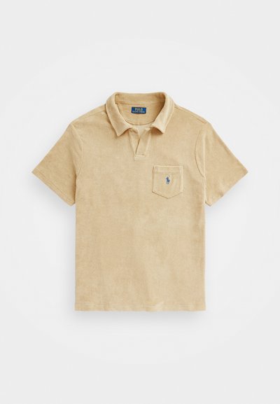 Polo en tissu éponge beige avec un col, des manches courtes et une poche poitrine dotée d'un logo brodé. Texture douce et design décontracté.