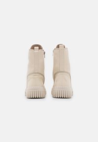 Botines beige de material suave con textura lisa, con cremalleras laterales, puntera redondeada y suela de goma estriada.
