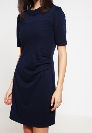 Marineblaues Kleid mit kurzen Ärmeln, geripptem Material und einem Bootsausschnitt. Es hat eine figurbetonte Silhouette und dezente Drapierungen an der Taille.