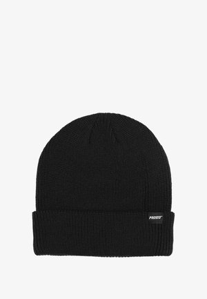 Czarna dziana czapka z prążkowaną fakturą, z podwiniętym mankietem i małą metką z logo po boku. Prosty, funkcjonalny design.