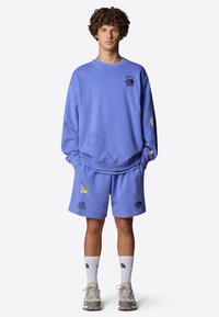 Conjunto de sudadera y pantalones cortos de color azul claro con diseños bordados que incluyen un sol y un caracol. Fabricado con tela suave, presenta un corte relajado.