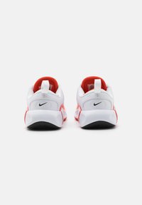 Witte sportschoenen met rode accenten, uitgerust met een gestructureerde mesh bovenkant, een gevoerde kraag en een contrasterende zwarte rubberen zool.