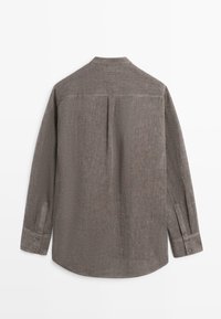 Grijs linnen overhemd met lange mouwen, geknoopte manchetten, een rugstuk en een centrale plissé in het midden van de rug, getoond van achteren op een witte achtergrond.