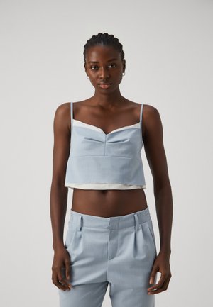 Light blue cropped top with thin straps and a v-neck design, featuring a white inner lining and subtle vertical texture.