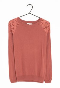Maglione a maniche lunghe color ruggine con pannelli di pizzo floreale sulle spalle appeso a una gruccia nera su uno sfondo bianco.