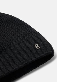 Czarna, dziana czapka typu beanie o prążkowanej strukturze, z metalowym akcentem w kształcie litery "B". Czapka jest przedstawiona z bliska, podkreślając jej materiał i kształt.