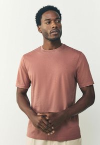 Kortærmet t-shirt med rund hals i en støvet rosa farve, lavet af blødt bomuldsstof, med en glat tekstur og et enkelt design.