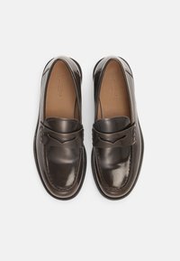 Smeđi kožni mokasini s glatkim završetkom, s ukrasnim remenčićem i detaljima šavova, okruglim vrhom i niskim gumenim potplatom.