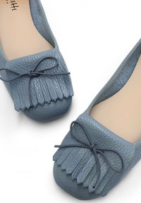 Ballerines en cuir bleu avec un design frangé et un nœud sur le bout. Texture lisse avec une forme arrondie et une doublure douce.