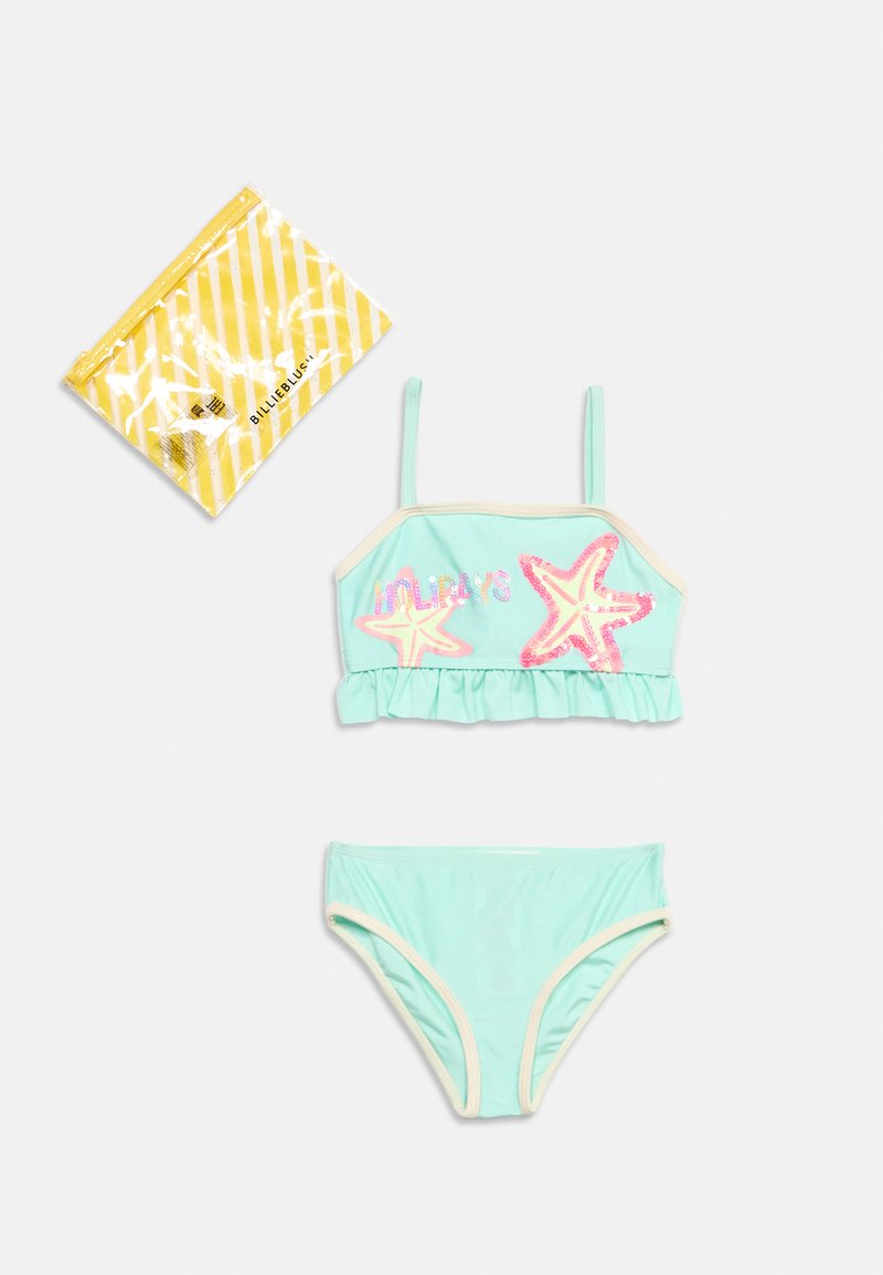 Maillot de bain deux pièces bleu clair pour fille avec des motifs d'étoiles de mer roses et un bord à volants, à côté d'un sac d'emballage rayé jaune.