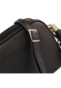 Zwarte leren handtas met een getextureerd oppervlak, gouden gesp, verstelbare band en ritssluiting.