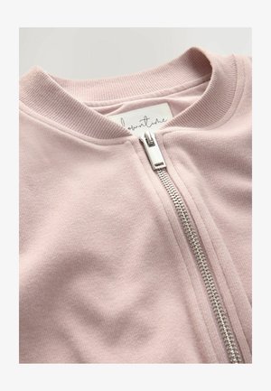 Light pink zip-up jacket featuring a ribbed collar and silver zipper, made of soft fabric with a smooth texture and subtle sheen.