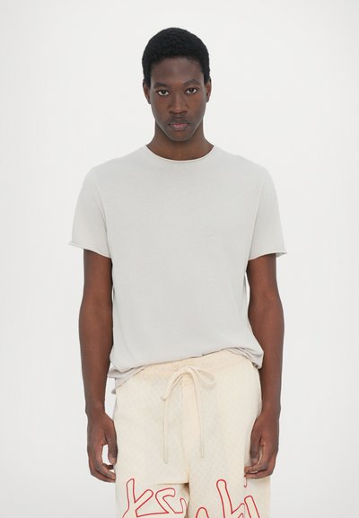 Camiseta de manga corta gris claro con escote redondo, combinada con pantalones cortos de textura beige con letras rojas. Tejido suave, corte casual.