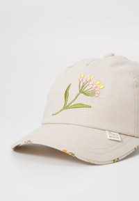 Beige Kappe aus Stoff mit einem gestickten Blumenmuster in Pink und Gelb. Verfügt über einen genähten Schirm und ein gemustertes Innenfutter.