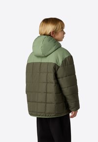 Sötét olívazöld és világoszöld párnázott dzseki, steppelt mintával és kapucnival. Laza szabású, sima tapintású.