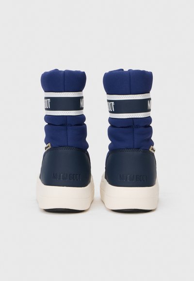 Tengerészkék Moon Boot, párnázott textil felülettel és gumírozott sarokkal. Fehér logós szalaggal és tömör krémszínű talppal rendelkezik.