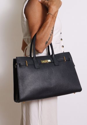 Borsa a mano nera in pelle con una forma strutturata, superficie testurizzata, dettagli in oro e due manici superiori.