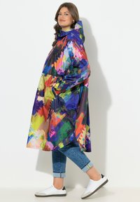Impermeabile colorato con cappuccio, caratterizzato da un motivo astratto in blu, verde, giallo e rosso. Design leggero, lunghezza fino al ginocchio.