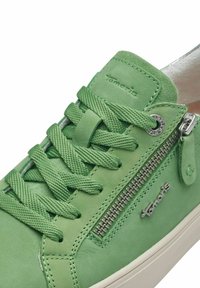Zapatilla de cuero verde con cordones texturizados y cremallera lateral, que presenta un acento de logo plateado y una suela blanca contrastante.
