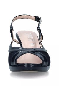 Scarpa slingback in vernice nera con punta aperta, dettagli incrociati e soletta beige a contrasto. Cinghietta regolabile con fibbia.