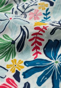 Kolorowa tkanina florystyczna z niebieskimi, różowymi, żółtymi i zielonymi wzorami. Gładka tekstura z różnorodnymi kształtami liści i kwiatów na jasnym tle.