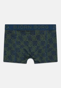 Un boxer en tissu vert foncé, présentant un motif répétitif de visages souriants en bleu marine. La taille est en bleu marine uni avec le logo "BJÖRN BORG".