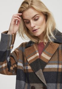 Plaid wool coat in brown, gray, and navy, featuring a notched collar and double buttons with a soft texture.