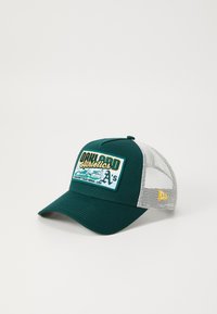 Grønn trucker cap med et brodert merke på fronten som har teksten "Oakland Athletics". Mesh bak og buet brem. Gul aksentlogo på siden.