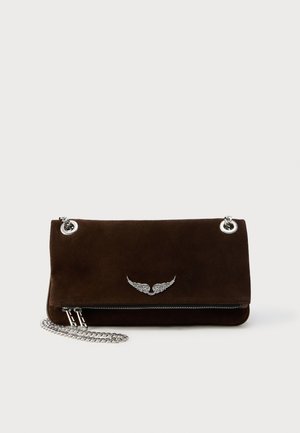 Pochette en daim marron avec bandoulière chaîne argentée, comprenant un compartiment zippé et un détail décoratif en forme d'aile argentée sur le devant.
