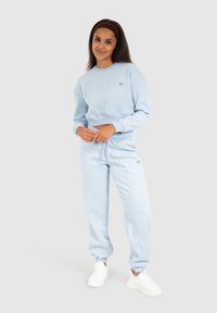 Felpa azzurra chiara e pantaloni jogger coordinati in morbido tessuto, con polsini a costina, un piccolo logo e una fascia elastica in vita con lacci.