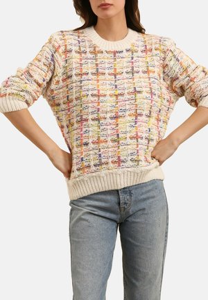 Pull en tricot avec un motif tissé coloré dans des teintes pastel. Présente un col rond et des poignets et un ourlet côtelés. Associé à un jean bleu clair.